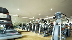 Een sportschool met meerdere cardio-apparaten, waaronder loopbanden en crosstrainers, in rijen opgesteld.