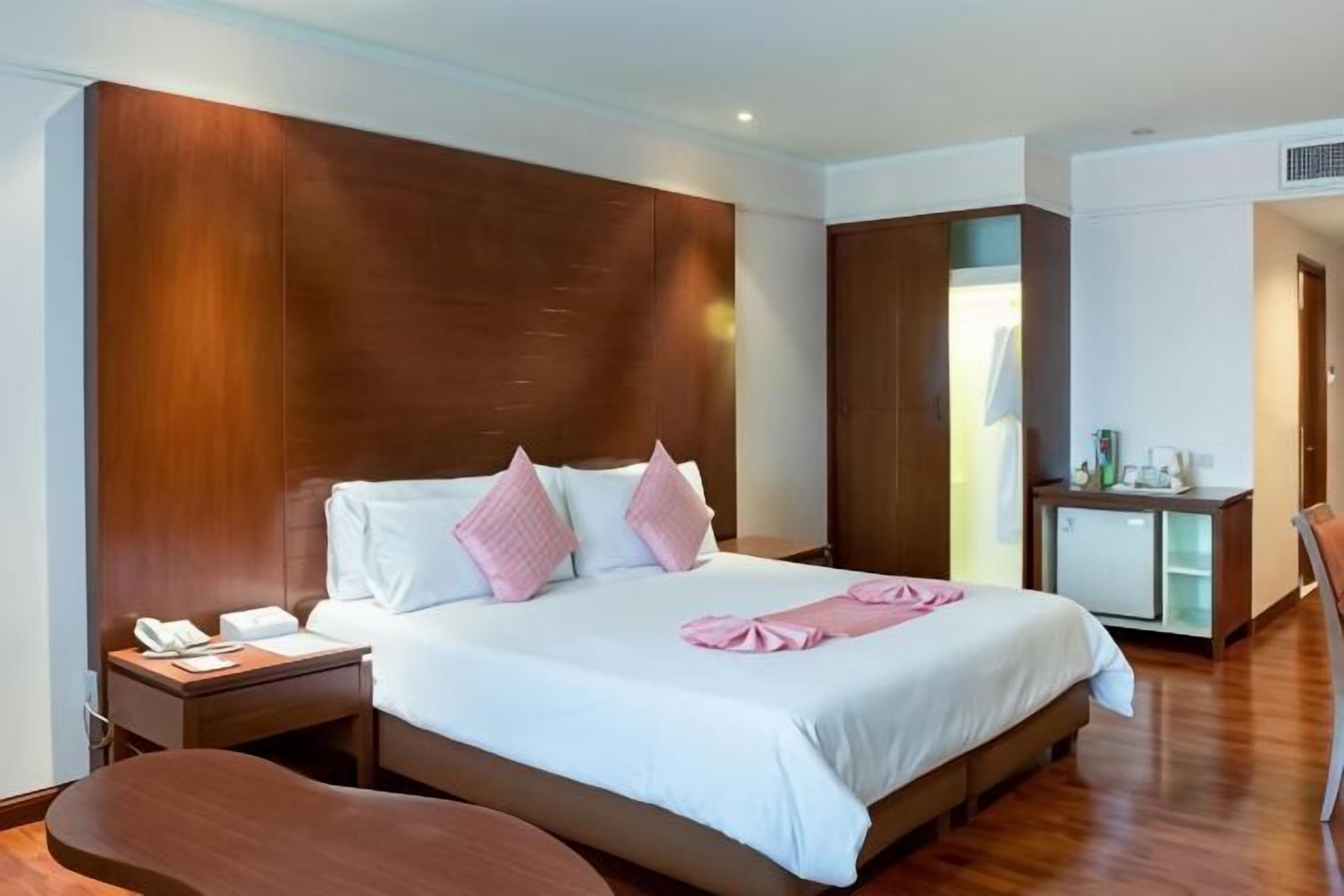 Ein Hotelzimmer mit einem großen Bett, Nachttischen, einem Schreibtisch und einem Kleiderschrank.