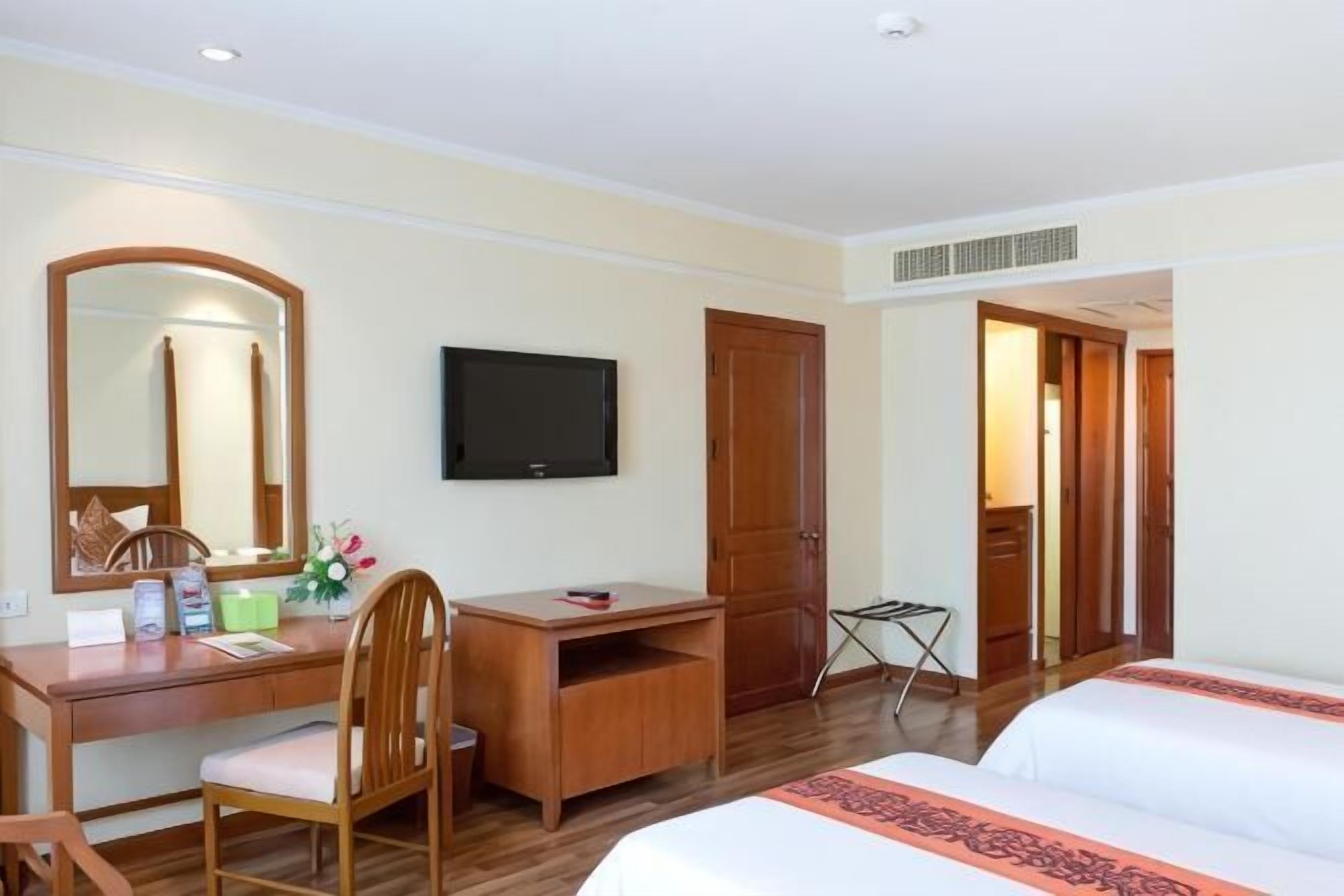 Ein Hotelzimmer mit Bett, Schreibtisch mit Stuhl, Fernseher und Kleiderschrank.