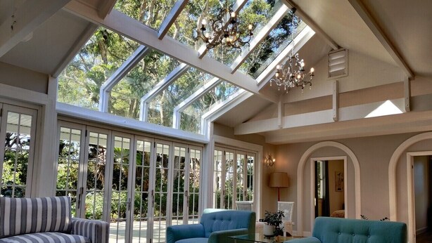 Une pièce spacieuse avec un plafond haut, de grandes fenêtres et un lustre.