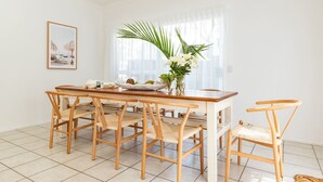 Un coin repas avec une table et des chaises en bois, un vase rempli de fleurs et un tableau encadré au mur.