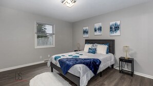 Un dormitorio con cama, mesita de noche y ventana con persianas.