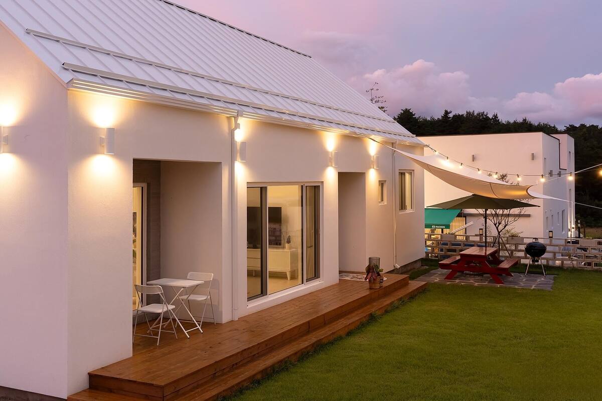 A modern house with a covered patio, outdoor seating, and a well-lit exterior.
