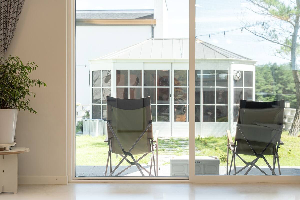 A room with a large sliding glass door leading to a covered outdoor area with two folding chairs.