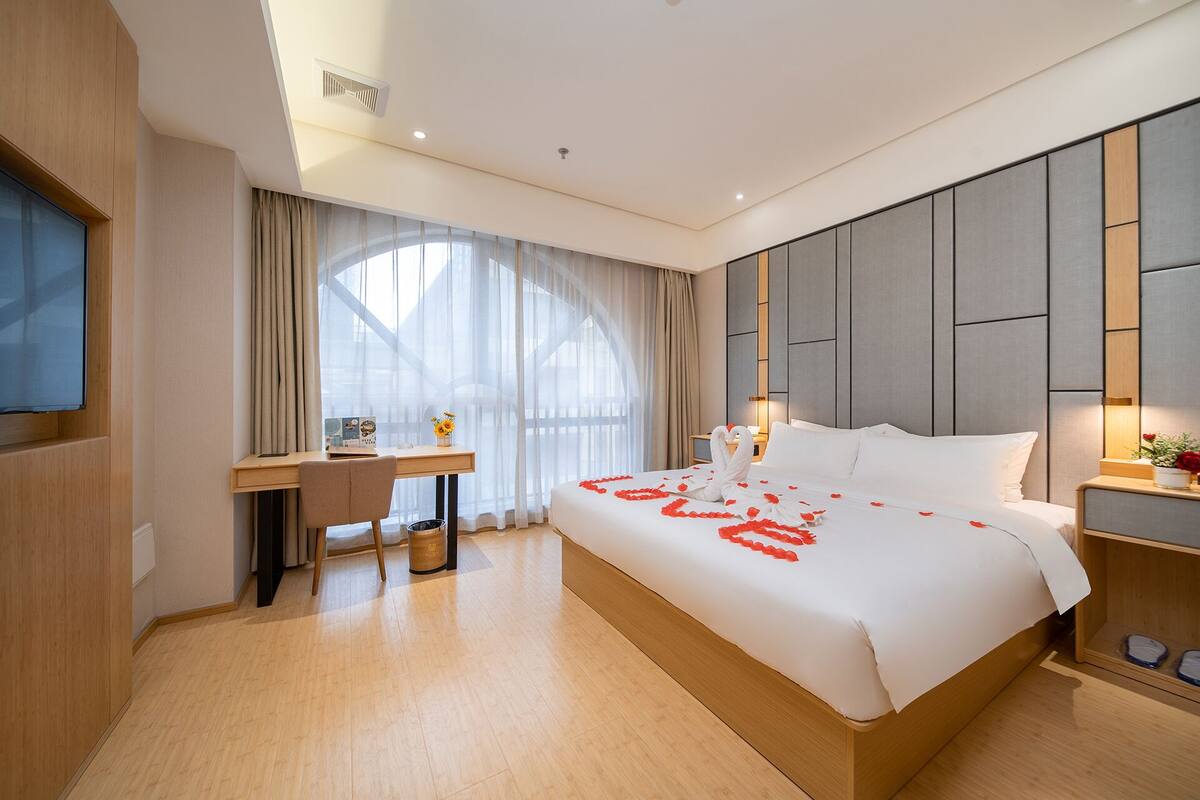 A hotel room with a large bed, a desk, and a TV.