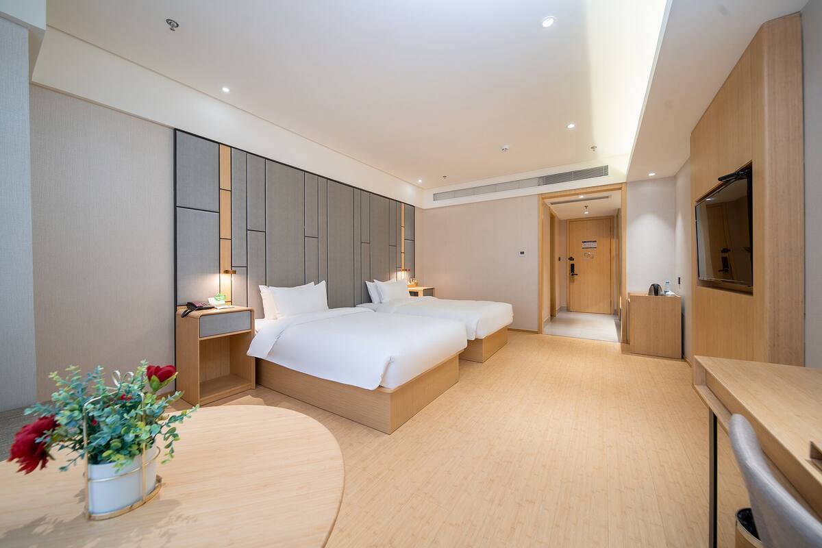 A hotel room with a large bed, bedside tables, a TV, and a wooden cabinet.