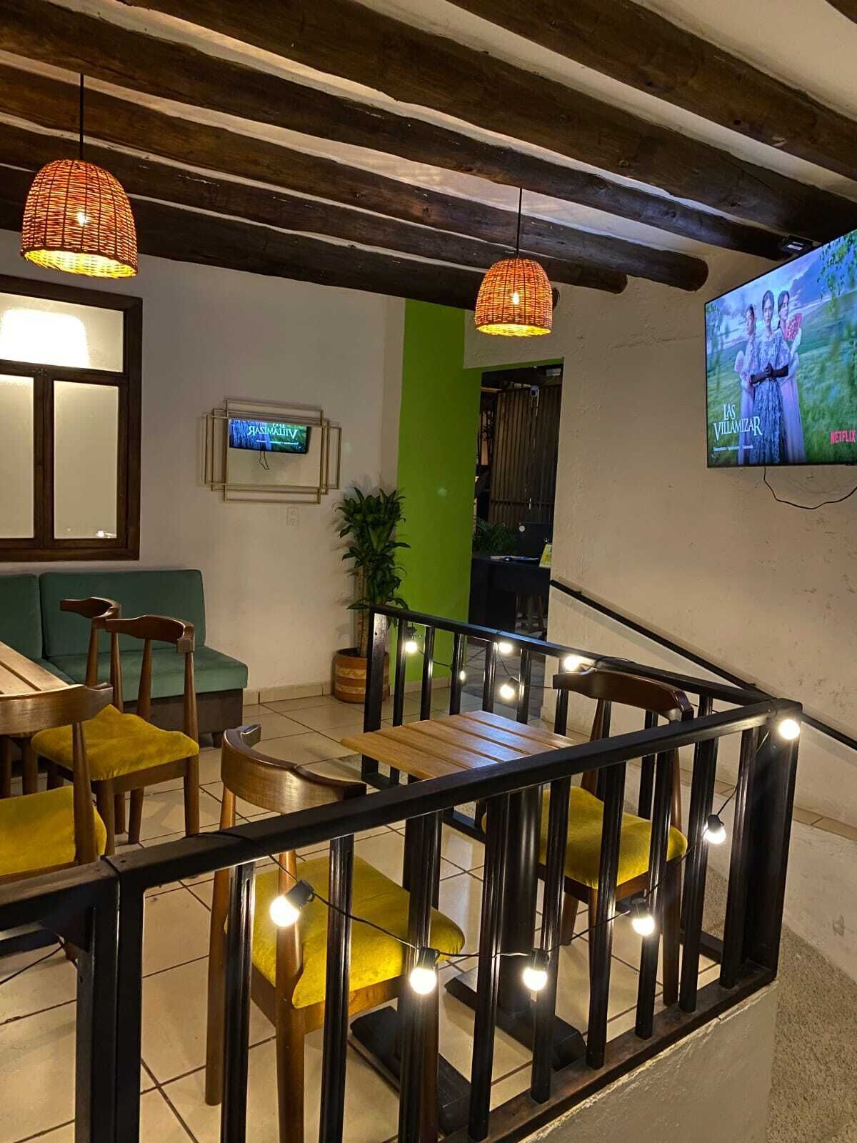 A modern interior with a wooden staircase, green walls, and a TV displaying 'Las Villamizar'.