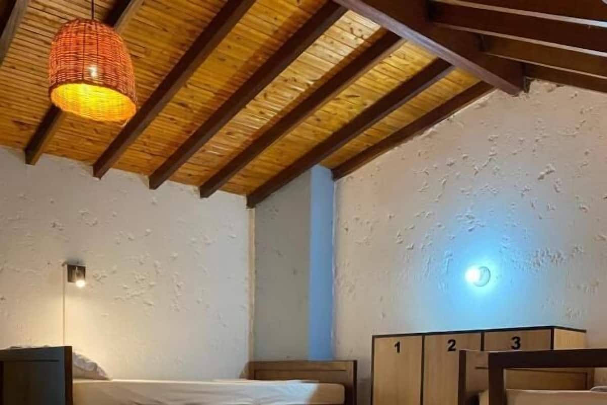 A small, compact room with a bunk bed, a wardrobe, and a hanging light fixture.