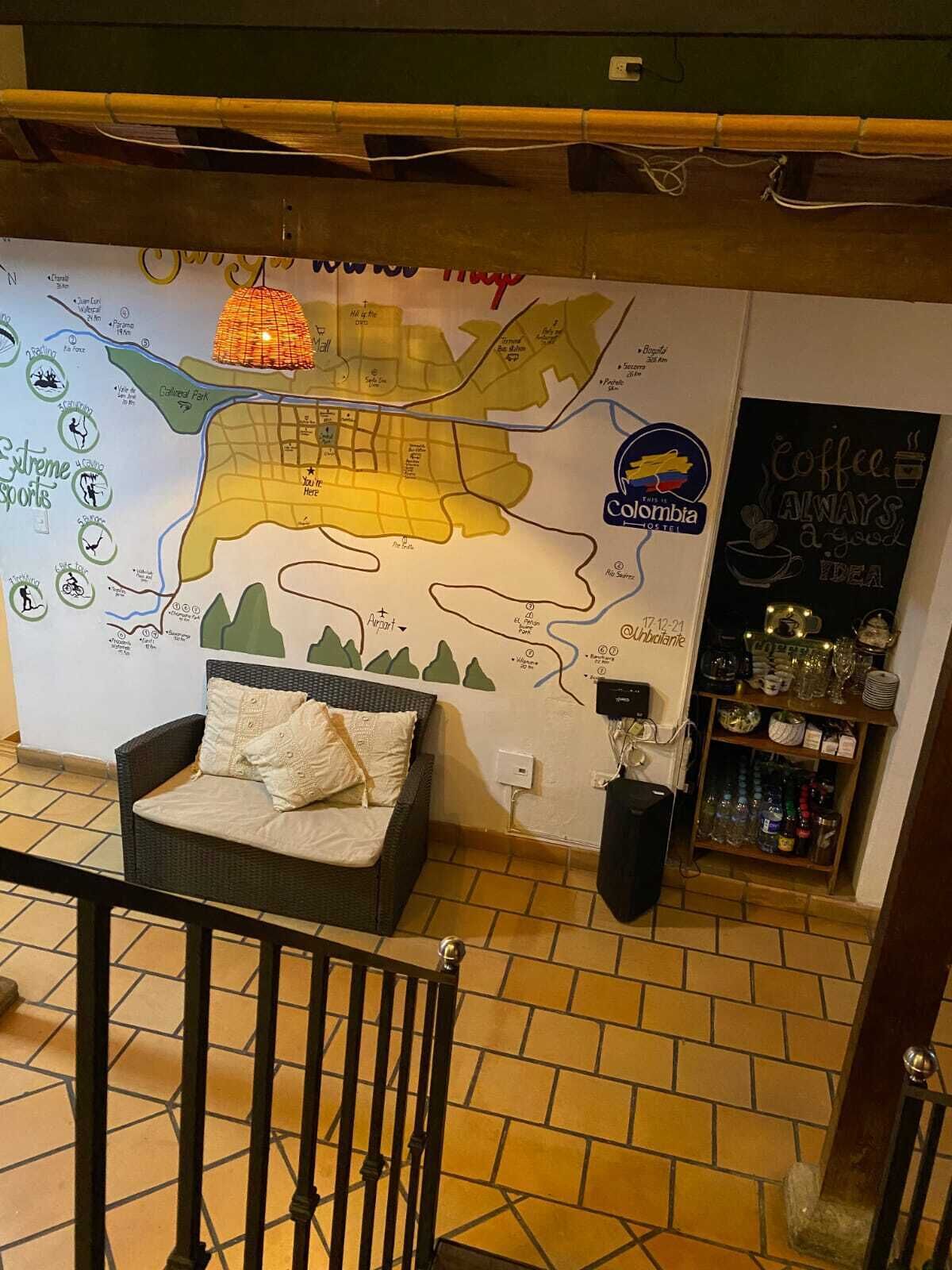 Una habitación con un mapa en la pared, un sofá, una cafetera y una estantería con botellas.
