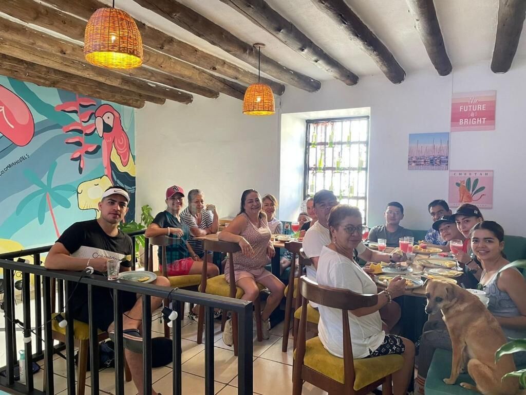 A group of people dining in a restaurant with a rustic interior, wooden beams, and a colorful mural on the wall.
