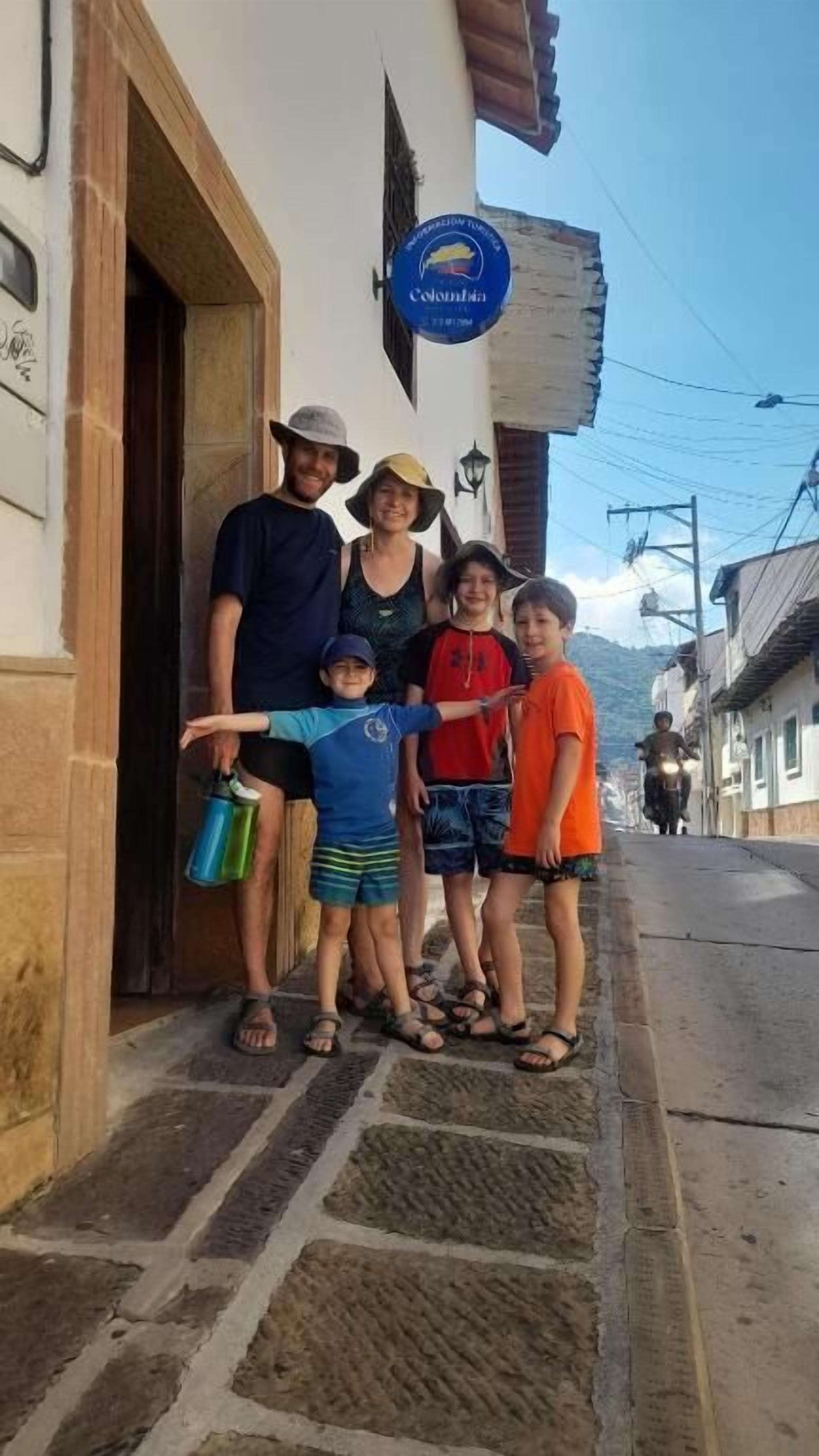 A family standing in front of a building with a sign that reads "Colonia."