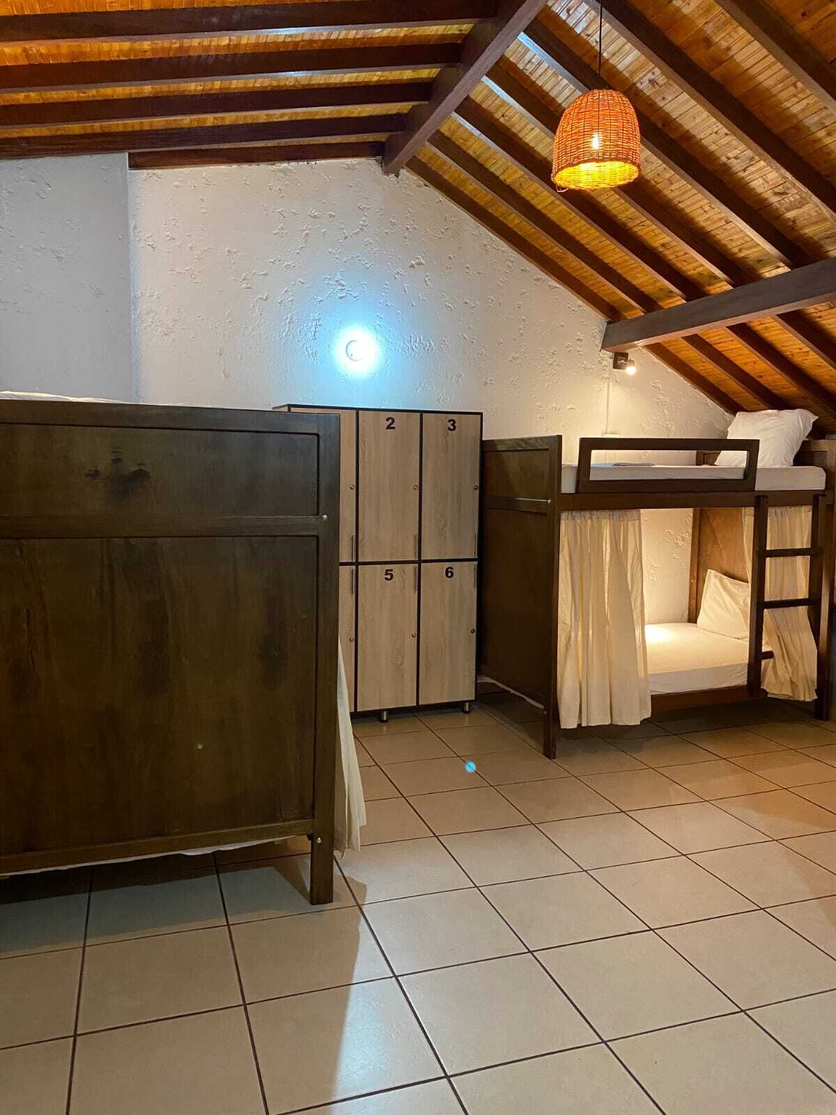 A dormitory room with bunk beds, a wardrobe, and a hanging light fixture.