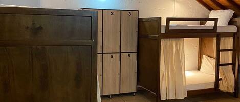 A dormitory room with bunk beds, a wardrobe, and a hanging light fixture.