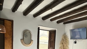 Une chambre à coucher avec un lit, un miroir, une télévision et une fenêtre donnant sur un beau paysage.