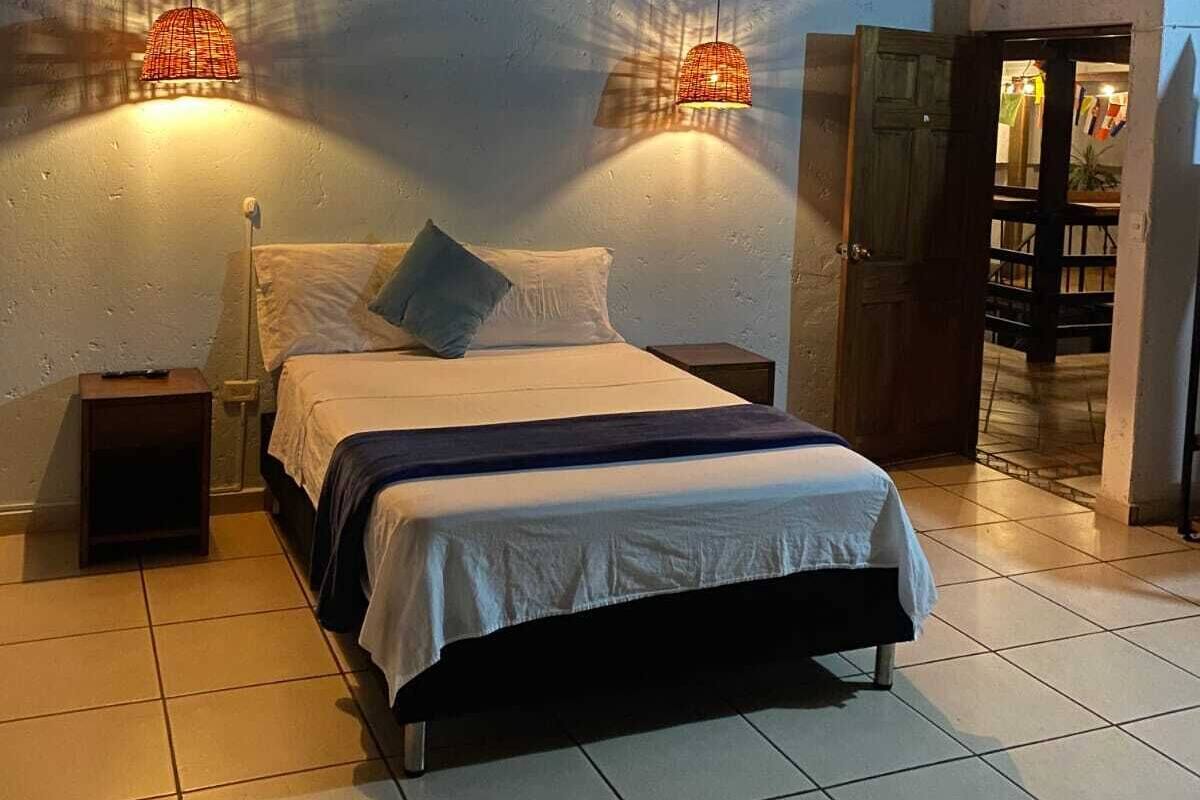 A bedroom with a bed, nightstands, and two wall-mounted lamps.