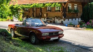 Un'auto decappottabile rossa d'epoca parcheggiata in strada.