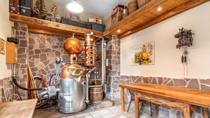 Una distilleria con alambicchi di rame, pareti in pietra, una panca di legno e un orologio appeso al muro.