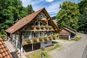 A traditional chalet with a sloped roof, dormer windows, and a balcony with flower boxes.