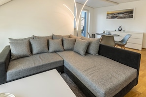 Un salon moderne avec un canapé d’angle, une table basse blanche et un coin repas comprenant une table et des chaises.