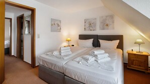Ein Hotelzimmer mit zwei Betten, einem Holzschrank, einem Nachttisch mit Lampe und Bildern an den Wänden.