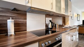 Eine moderne Küche mit einer Holzauszug, Edelstahlgeräten und einem eingebauten Backofen.