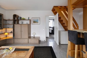 A modern kitchen with wooden cabinets, a dining table, and a staircase leading to an upper level.