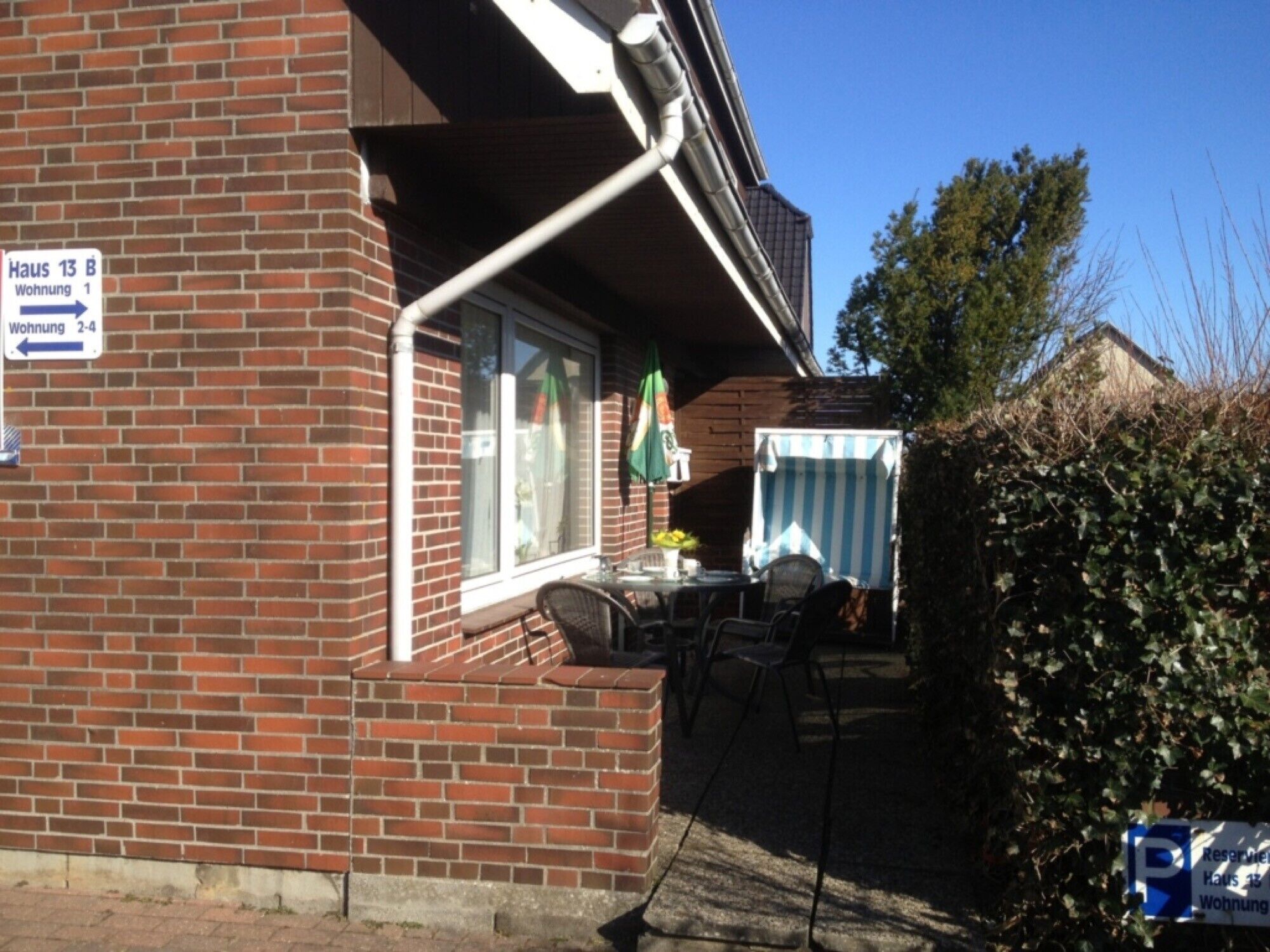 Un bâtiment en briques avec une enseigne indiquant les numéros des pièces et un patio aménagé avec du mobilier d’extérieur.