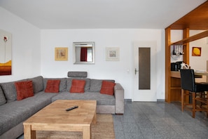 Una sala de estar con un sofá, una mesa de centro y un comedor con una silla.