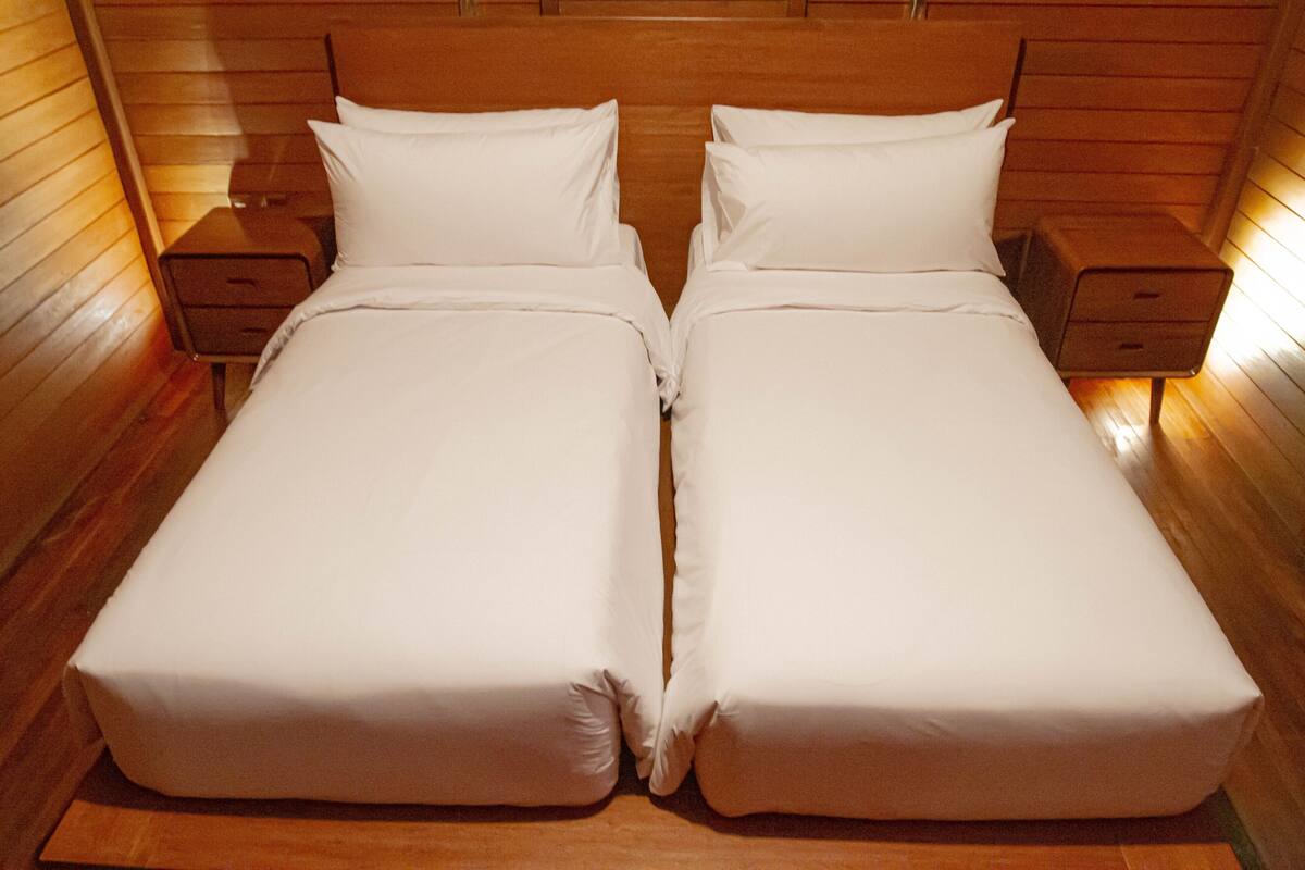A double bed with white linens in a wooden room.