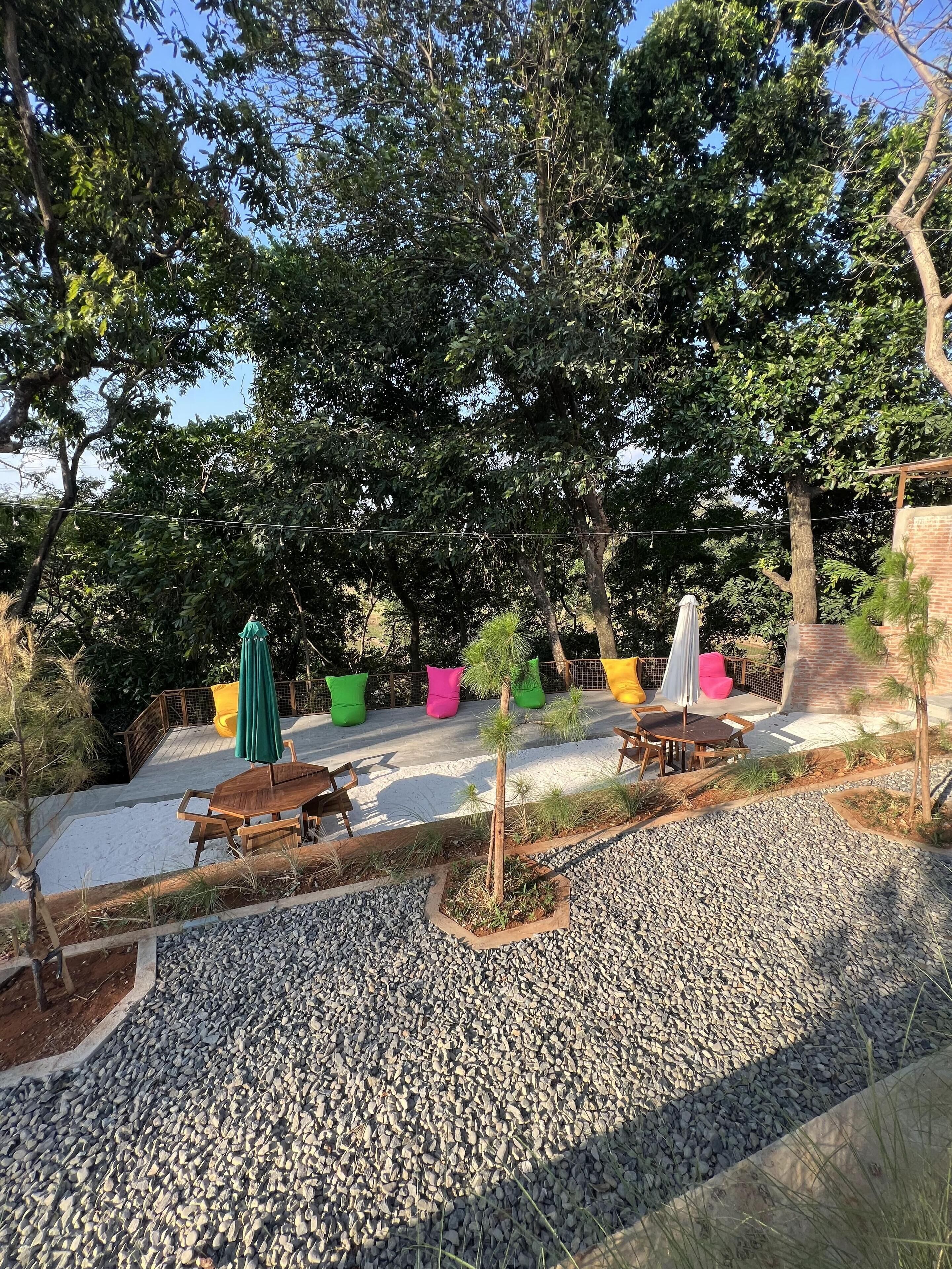 Eine Terrasse mit Sitzgelegenheiten im Freien, einem kleinen Baum und einem Kiesweg.