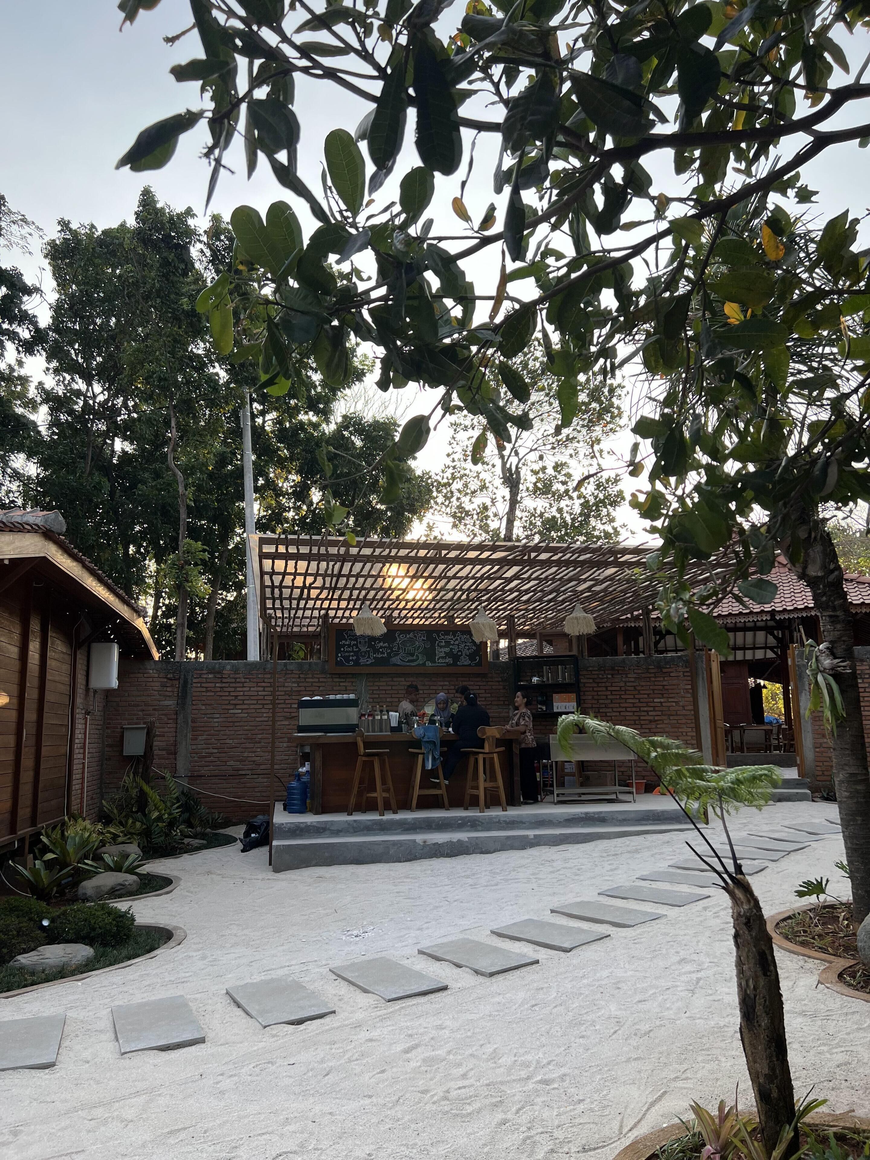 An outdoor seating area with a brick wall, a pergola, and a menu board.