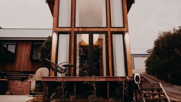 Ein modernes, zweistöckiges Haus mit großen Fenstern und einer Holzterrasse.
