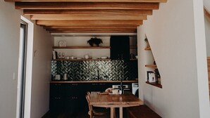 Eine moderne Küche mit Holzschränken, einer Fischgrät-Spritzschutzleiste und einem Essbereich mit Holztisch und -stühlen.