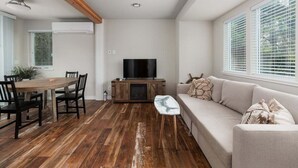 A modern living room with a wooden dining table, a sofa, and a TV.