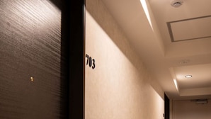 A hallway with a dark wooden door labeled '703', a carpeted floor, and a ceiling with recessed lighting. - JA Hotel Namba (Osaka)