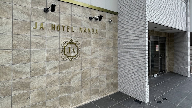 The exterior of JA Hotel Namba, featuring a modern facade with a tiled entrance and a prominent hotel logo. - JA Hotel Namba (Osaka)