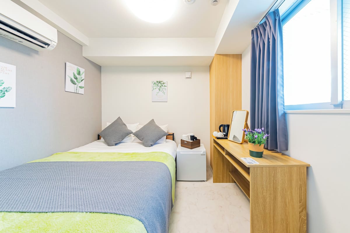 A neatly arranged bedroom with a bed, bedside table, and a small desk with a chair.