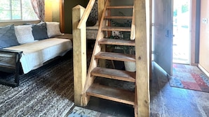 A wooden staircase leading to a loft bedroom with a bed and a window. - Clean cozy cabin within 1/2 mile of 2 lakes and 100’s of sq miles of wilderness. (West)
