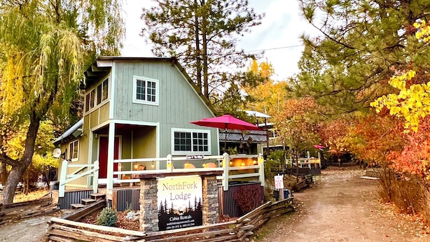 A lodge with a two-story structure, a covered porch, and a sign indicating it offers cabin rentals. - Clean cozy cabin within 1/2 mile of 2 lakes and 100’s of sq miles of wilderness. (West)