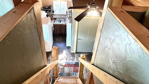 A wooden staircase leading to a kitchen with a ceiling fan and a window. - Clean cozy cabin within 1/2 mile of 2 lakes and 100’s of sq miles of wilderness. (West)