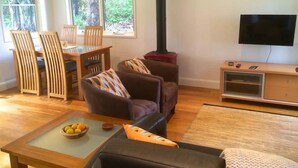 Ein Wohnzimmer mit Kamin, Fernseher und einem Essbereich mit Stühlen und Tisch.
