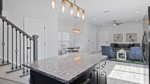 A modern kitchen with granite countertops, a central island, and pendant lighting.