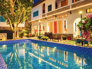 A swimming pool with a tiled edge, surrounded by outdoor furniture and a building with multiple windows and doors. - The Nam Du Hill (Kien Hai)