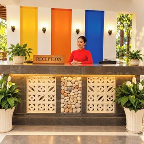 A reception desk with a 'RECEPTION' sign, potted plants, and a stone wall feature. - The Nam Du Hill (Kien Hai)