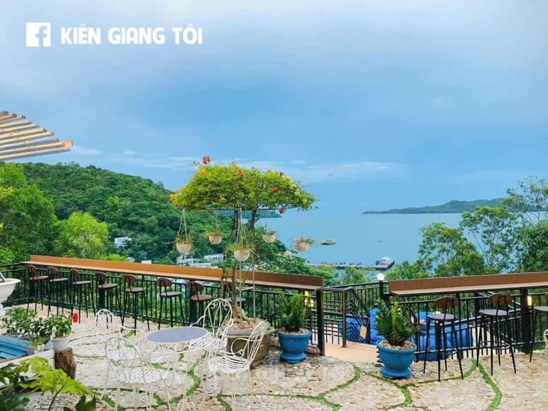Ein Sitzbereich im Freien mit Tischen und Stühlen, mit Blick auf ein Gewässer und Grünflächen.