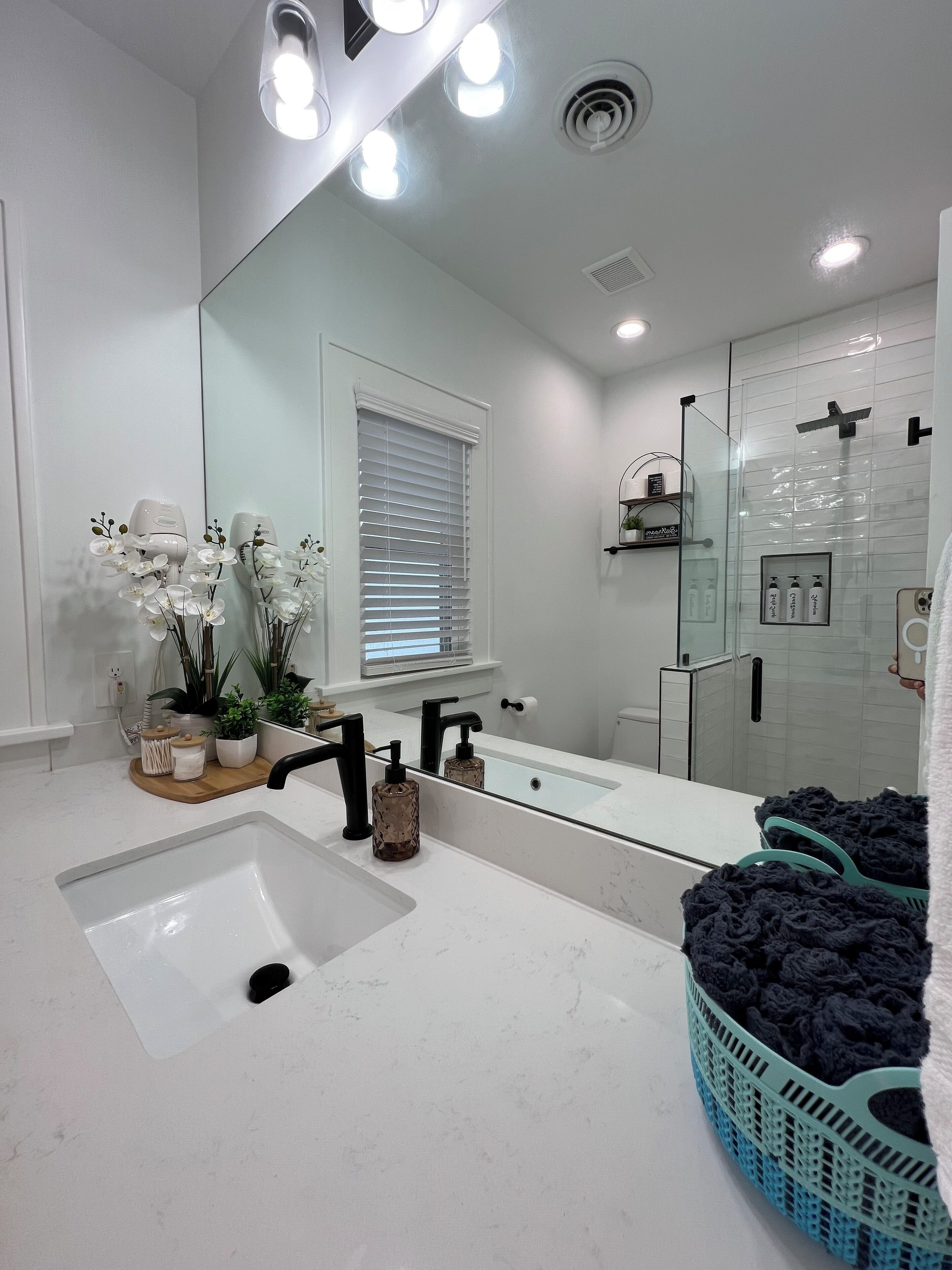 A modern bathroom with a large mirror, white sink, and a glass shower enclosure.