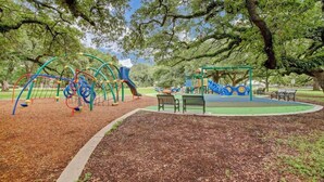 A playground with various play structures, benches, and a covered area.