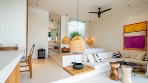 A modern living room with a white sofa, wooden side table, and a ceiling fan. - Casa Umalas Villa by Betterplace (Kerobokan)