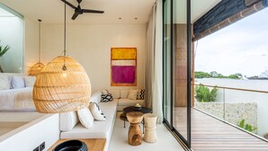 A modern living room with a sofa, hanging rattan light fixture, and a view of the sea. - Casa Umalas Villa by Betterplace (Kerobokan)