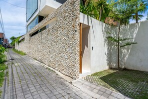 Un edificio moderno con fachada de piedra, un sendero pavimentado y un pequeño jardín.